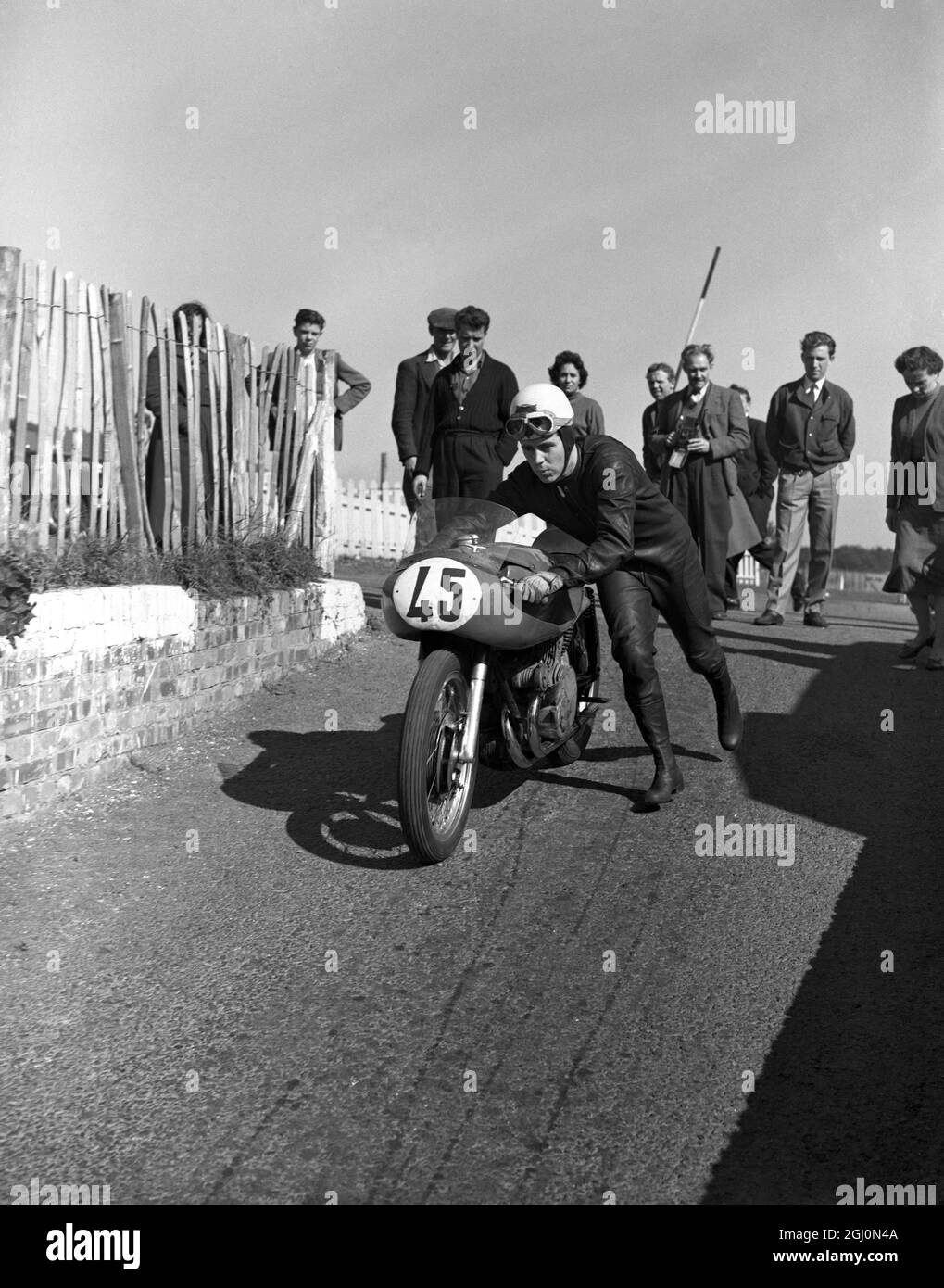 Geoff Duke , British world road racing motorcycle champion , setting off for another practise lap at the Brands Hatch racing circuit in Kent . 24th September 1955 Stock Photo