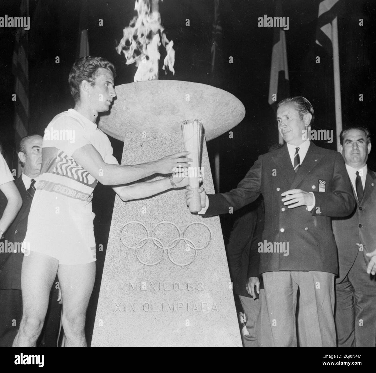 Madrid , Spain : Taking the Olympic torch is Spanish Olympic Commissioner , Juan Antonio Samaranch ( right ) . The handing over ceremony took place after the lighting of the Olympic flame on a permanent monument in Madrid ' s Columbus Square ( Plaza De Colon ) . 9 September 1968 Stock Photo
