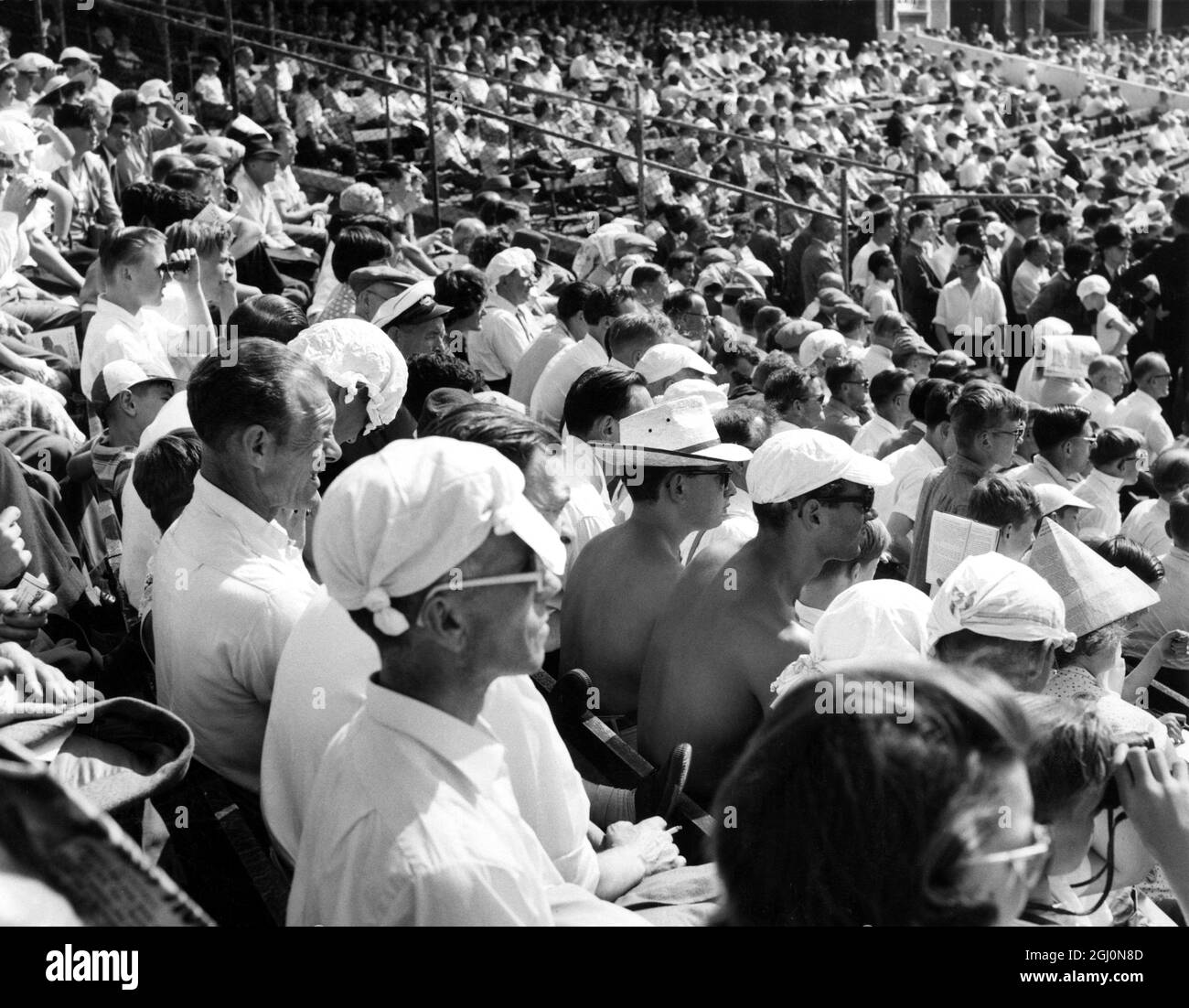 Unperturbed by recent etiquette violations at Lord's Cricket Ground , many members of the crowd who had come to see the first day of the Final Test Match stripped off jackets , shirts and vests , sitting with many makeshift types of sun hat in the warm August sunshine , many of whom are seen in this picture which was taken at The Oval , London , England . 20 August 1959 Stock Photo