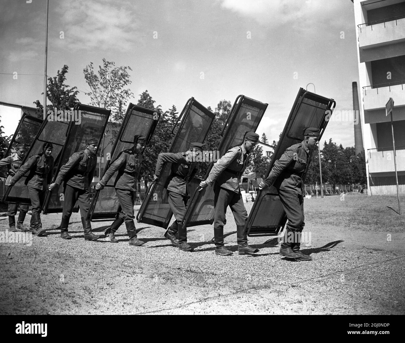 Helsinki , Finland : Shouldering beds that will be used by various Olympic contestants of different countries , are young Finnish soldiers . During part of their 12 months training they are helping to get the Olympic Village ready at Helsinki . 4th July 1952 Stock Photo
