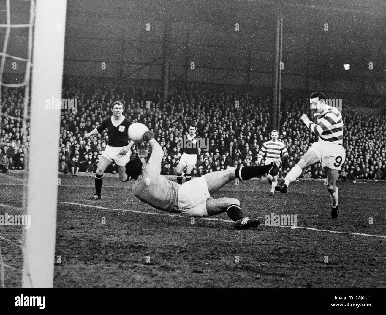 Glasgow ; Celtic centre - forward , Chalmers hits the ball hard at point - blank range but his fine effort is met with an equally fine save from the Dundee goalkeeper Arrol , during the Scottish First Division game played here . During the match , Arrol was beaten five times - the final score being 5 - 0 . 7 January 1967 Stock Photo
