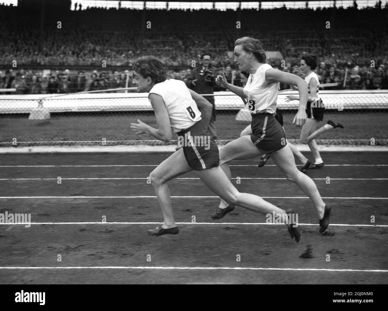 Marjorie Jackson takes over the baton on the last 110 yards from Winsome Cripps while setting a new world record of 46.3 seconds for the womens 440 yards relay event in the athletics match between the British Empire and the United States at the White City Stadium , London . 4th August 1952 Stock Photo