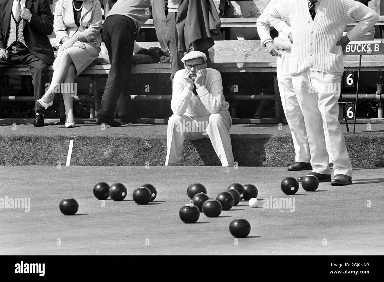 Walter Coulson , a member of the Leicester B team , casts a critical eye over the number of woods around the jack , whilst the opponents play their shots . Walter is pictured while playing in the annual National Bowling Championships , Mortlake , London , England . 17 August 1967 Stock Photo