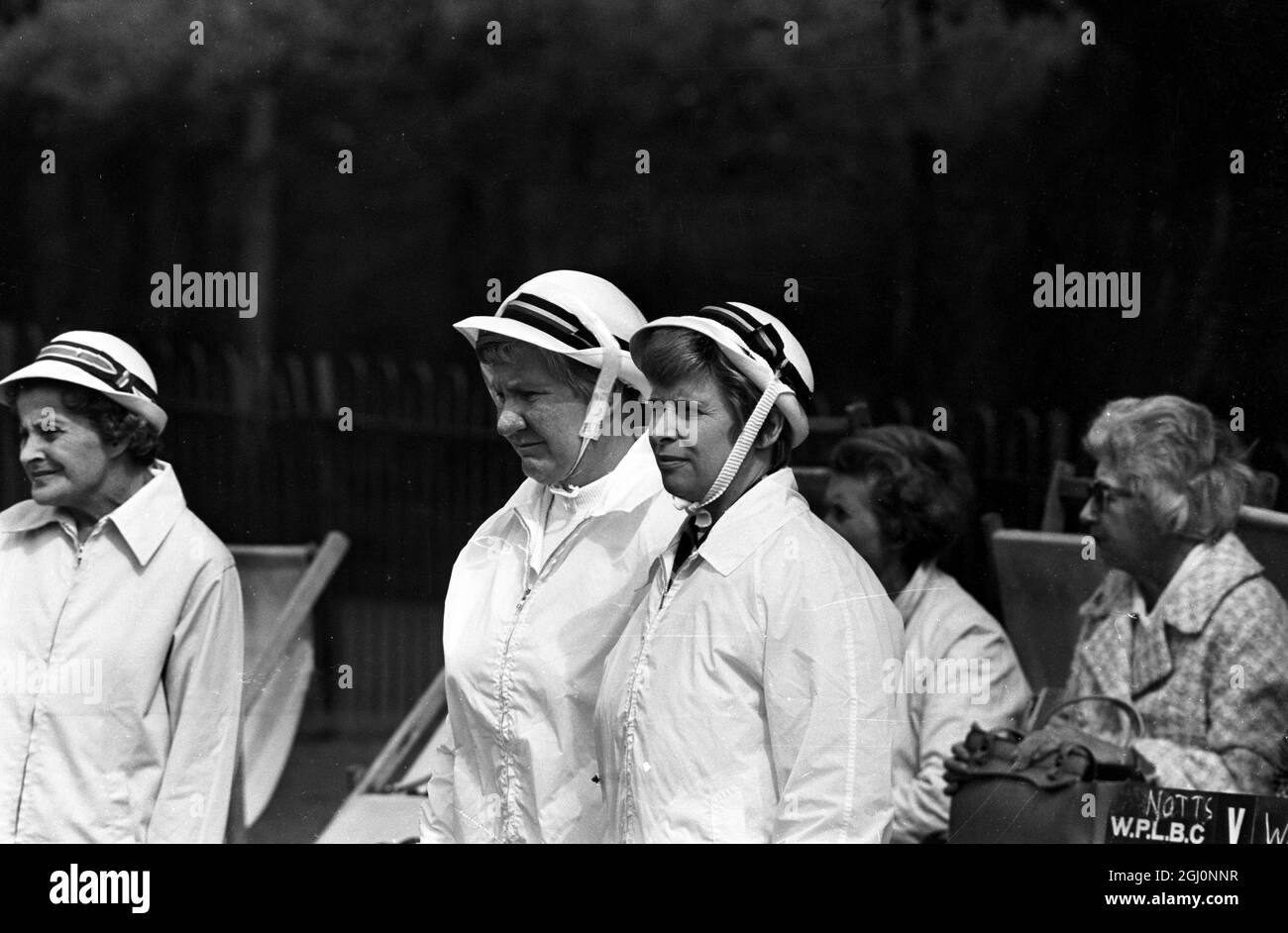 Two white clad women wear hat straps under their chins to prevent them falling , at the Amateur National Championships of the English Women's Bowling Association at Wimbledon Park , London , England . 25 August 1969 Stock Photo
