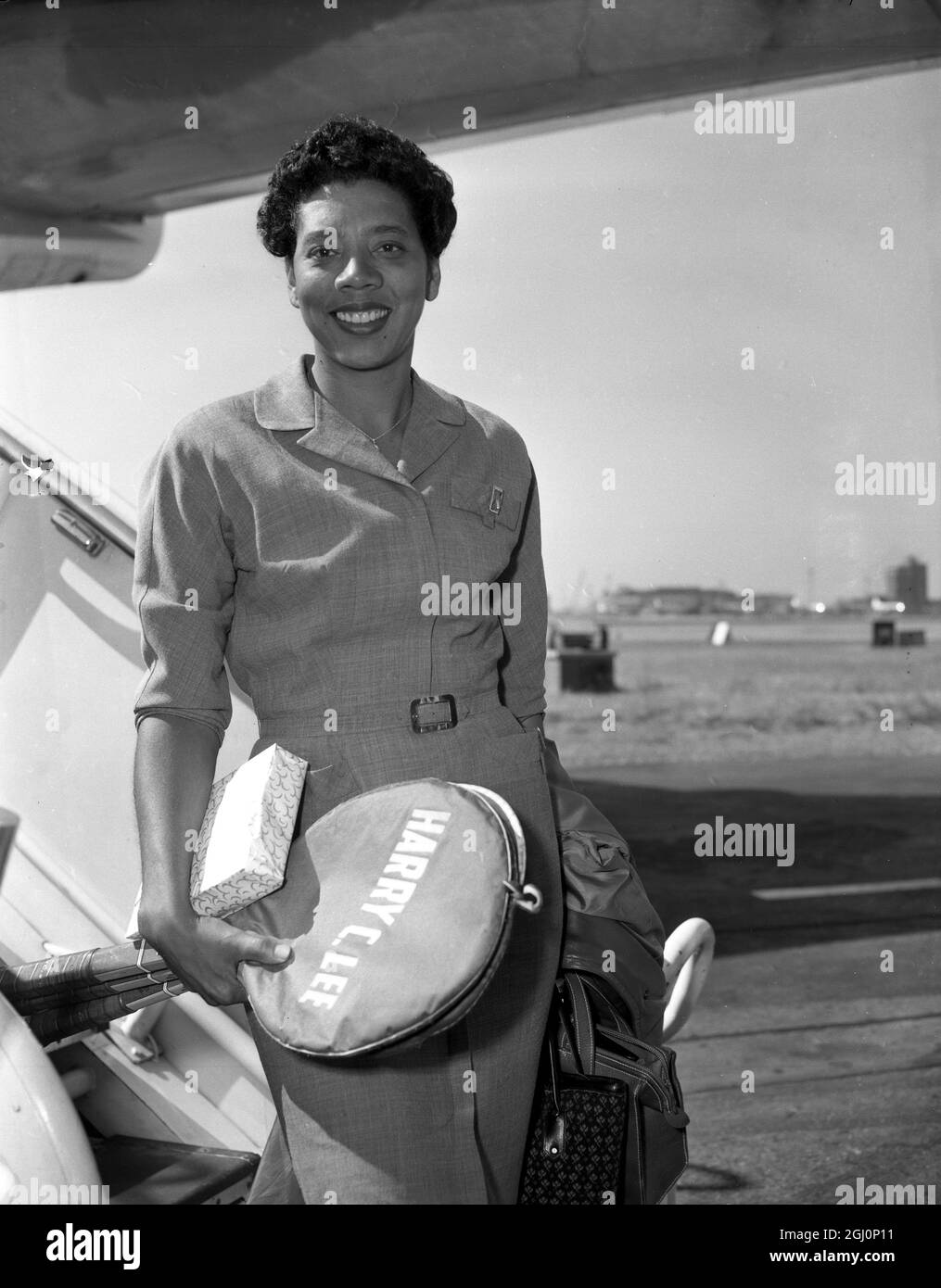 Althea Gibson , the reigning Wimbledon women 's champion , arriving here , tennis racquets in hand , at London Airport . Although not competing , Althea will be reporting on the Wimbledon Championship for an evening newspaper . 17th June 1959 Stock Photo