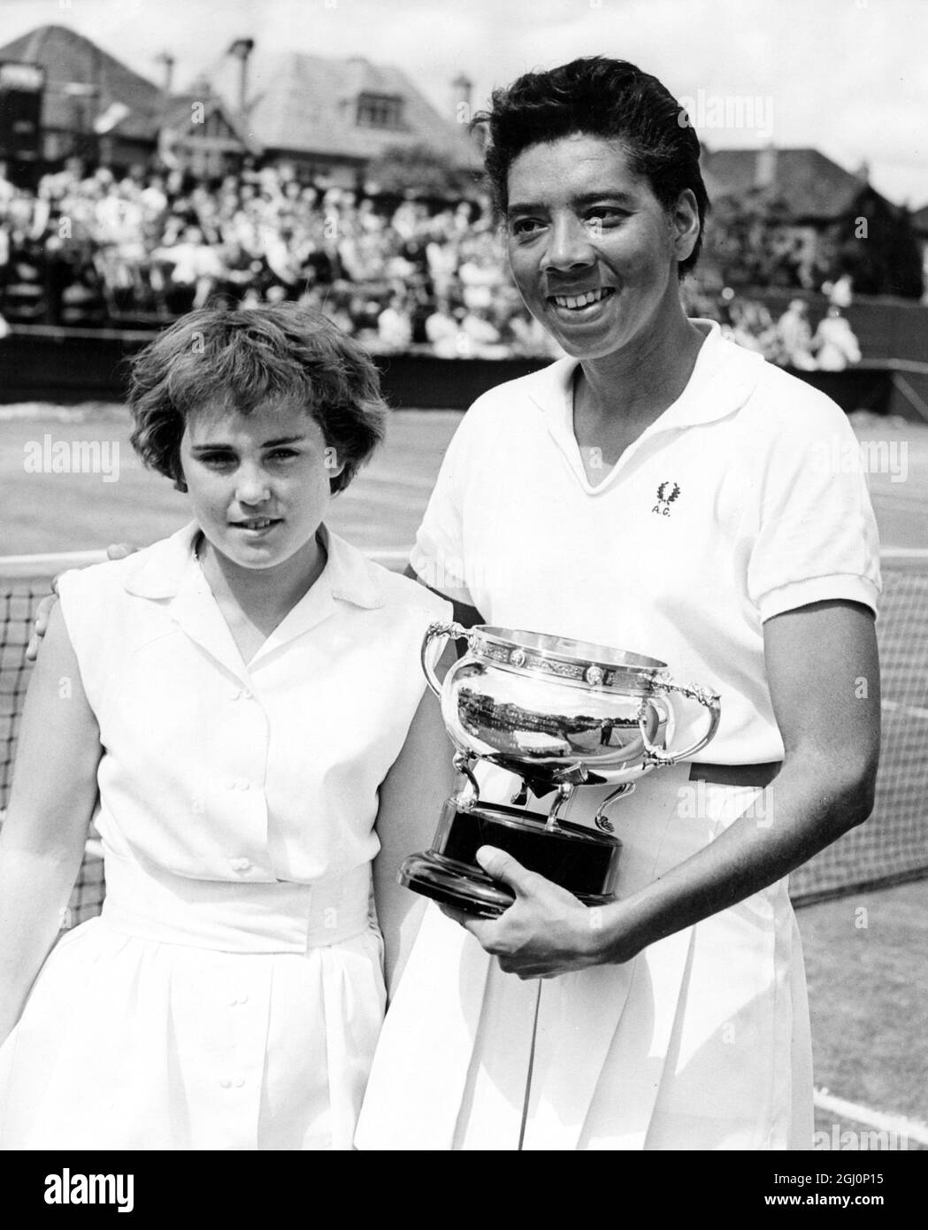 Miss Althea Gibson , the black American Wimbledon Champion , at the lawn tennis Surrey Championships in Subriton , which she has won . Here Althea poses with her trophy and the runner up Miss Mimi Arnold , also American . 31st May 1958 Stock Photo