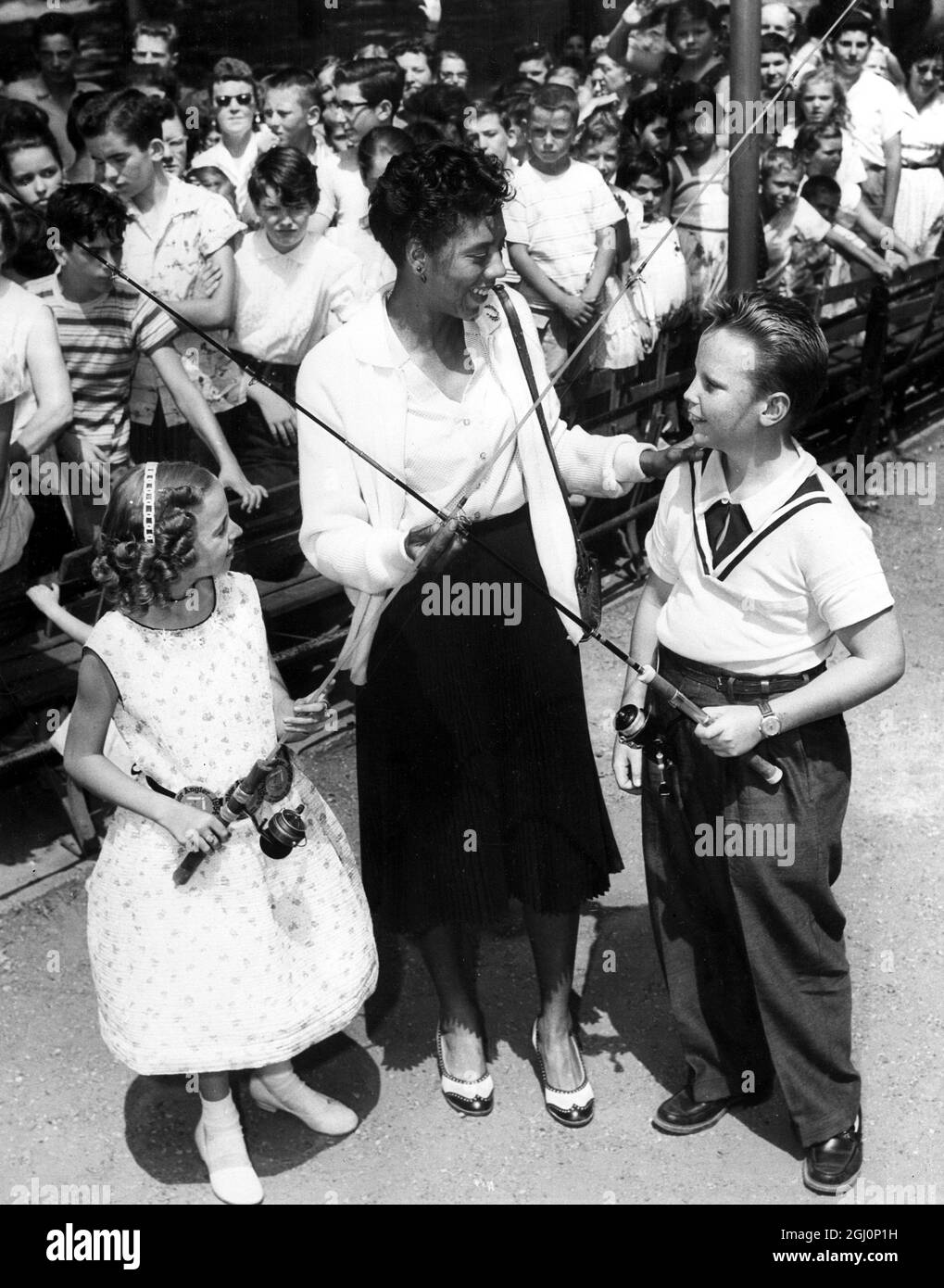The Wimbledon champion , Althea Gibson , congratulates the Abraham and Straus Junior Angler Contest winners , Diane Burgel , 10 , and Douglas Clark , 13 , at the victory fish - fry held in Prospect Park , Brooklyn , New York . 13th August 1957 Stock Photo
