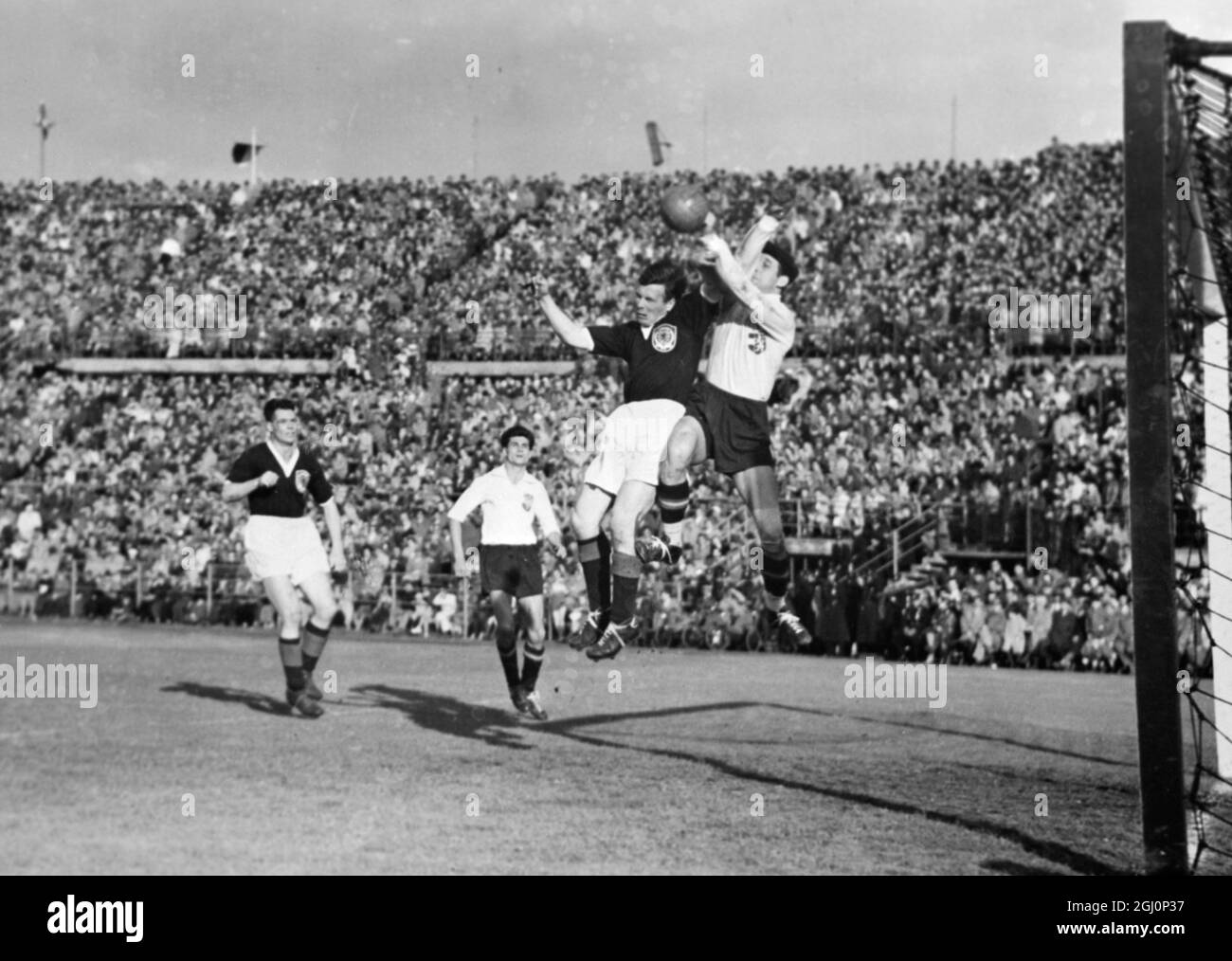A tussle for the ball in front of the football match between Austria and Scotland which Scotland won 4-1 at the Vienna Stadium . The Austrian goalkeeper Schmied and the Scots centre-forward Lawrie Reilly are going up together watched by Liddell (dark shirt) and Halla . 22 May 1955 Stock Photo