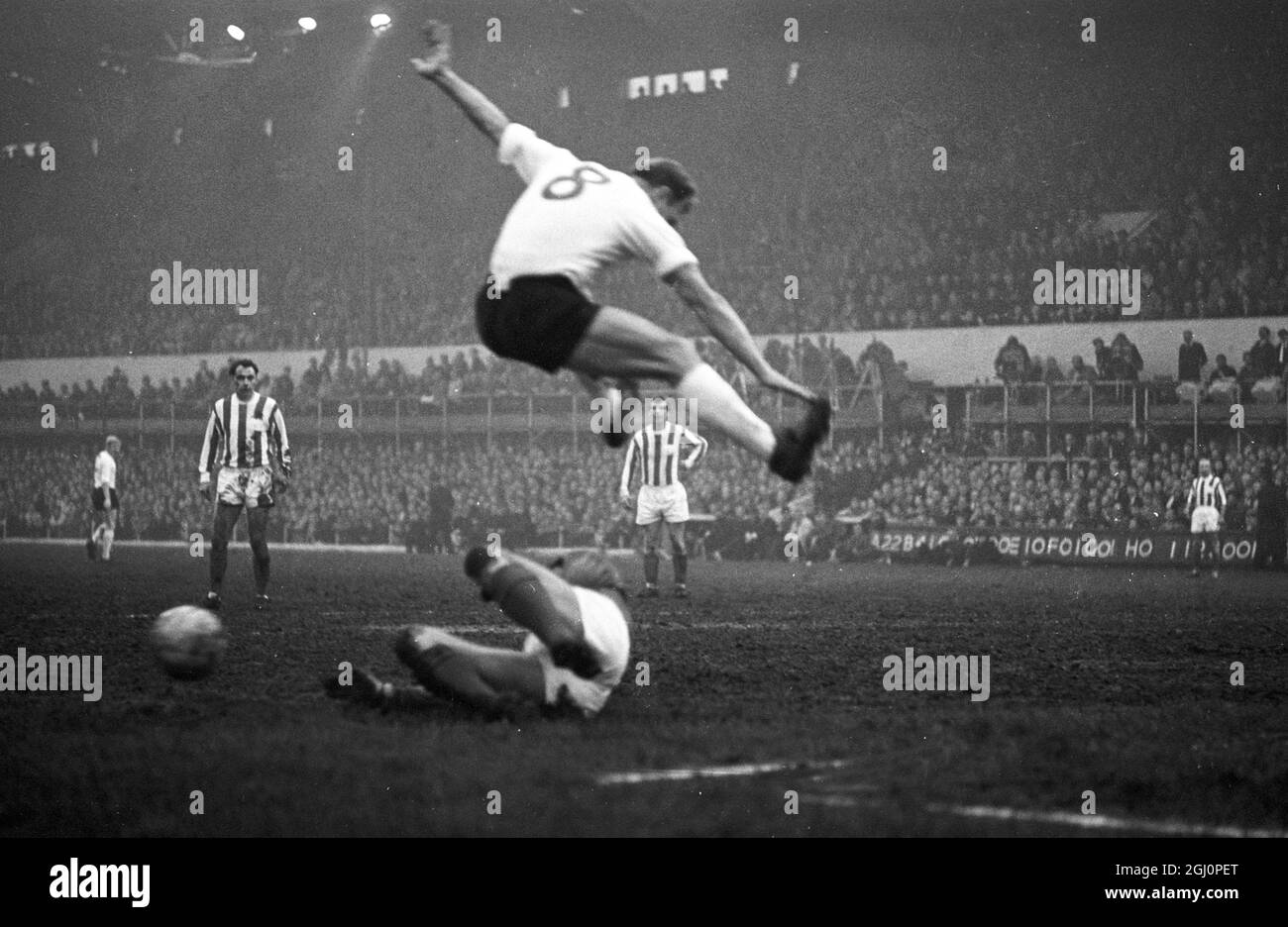 Stoke - on - Trent , Staffs , England ; Kubala of Spain playing in last night ' s World International side against Sir Stanley Matthew ' s side , leaps over English goalkeeper, Waiters , during the game . Sir Stanley ' s team were beaten 6 - 4 , but the score hardly mattered for Sir Stanley , the greatest name in soccer was bowing out majestically before 34 , 450 fans . The 50 - year old winger was chaired off by Lev Yashin and Ferenc Puskas of Honved , Real Madrid . 29 April 1965 Stock Photo