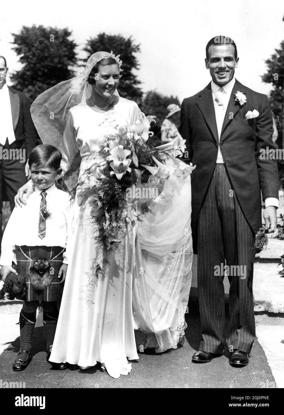 Miss Gwen Sterry, the English long tennis player, was married to Mr W.M. Simmers the Scottish rugby international player at Saint Marks Church, Surbiton, Surrey. A large gathering of tennis players attended, and Miss Betty Gwen Nuthall was among the bridesmaids. Photo shows the bride and groom with the tiny page master Hossack. 9 July 1932 Stock Photo