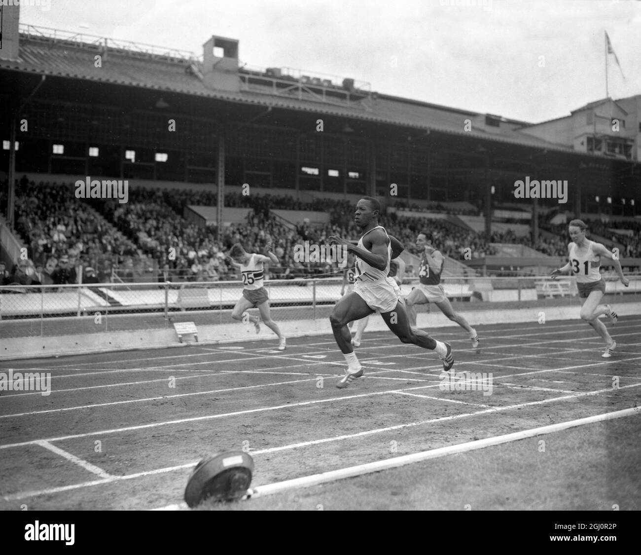 Cuban athlete Enrique Figuerola (no 1 ) streaks home to retain the 100 yards title for the second successive year at the Amateur Athletic Association Championships at the White City Stadium , London . Figuerola 's time was 9.6 seconds , Barry Kelly ( No 25 ) of Britain was second in 9.8 and Ming Campbell ( hidden by Figuerola ) of Glasgow University was third in 9.9 10 July 1965 Stock Photo