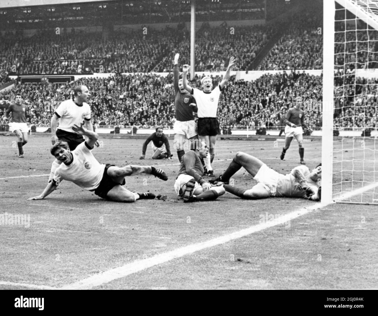 The goal that shook WembleyWembley, England : Yells from West German players Wolfgang Weber (white shirt, on ground) who scored, Uwe Seeler (white shirt, left) and Karl-Heinz Schnellinger (white shirt, centre) after they had equalised in the last few seconds of play in the World Cup Final at Wembley Stadium today. In extra time, England added two more goals to give the victory. England players in the picture are Ramon Wilson, (dark shirt on ground); Goalkeeper Gordon Banks; Captain Bobby Moore (behind Schnellinger); Jackie Charlton (background right); and George Cohen (background, centre). 30 Stock Photo
