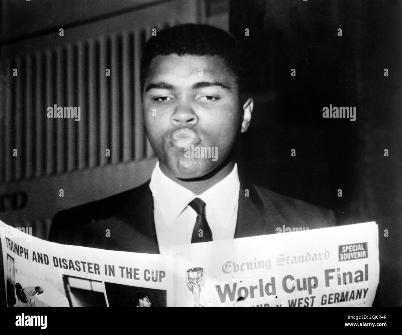Judgement day....London : How does a World Champion in boxing prophesy which team is to become World Champion i the Final of the World Cup Tournament at Wembley Stadium today? Who knows. But World Heavyweight Champion Muhammad Ali (Cassius Clay) looks as if he is considering all the angles as he studies the newspaper giving the form of the West German and England final later today. He is currently in Britiain to defend his title against Britain's Brian London at Warls Court, 6 August. 30 July 1966 Stock Photo