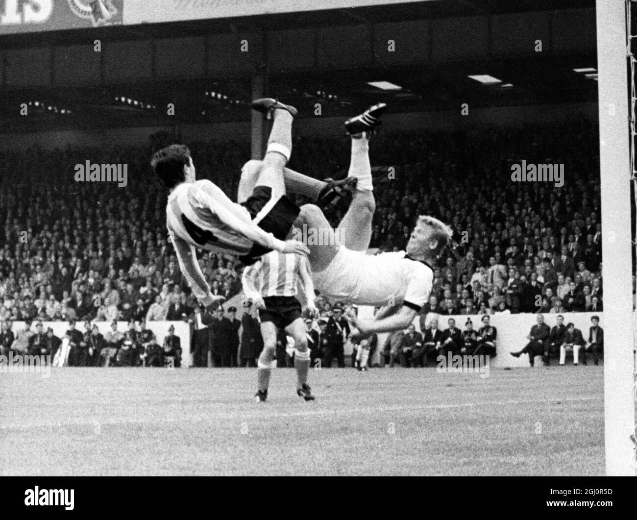 Now, the Tandem Kick 1966 World Cup Football One bicycle kick correctly executed makes the crowd gasp, two leaves them breathless. At Villa Park, Birmingham, the two in tandem are Argentina's Roberto Perfumo (on left) and West Germany's Helmut Haller. They were playing in Saturday's World Cup match, which ended in a goalless draw. 17 July 1966 Stock Photo