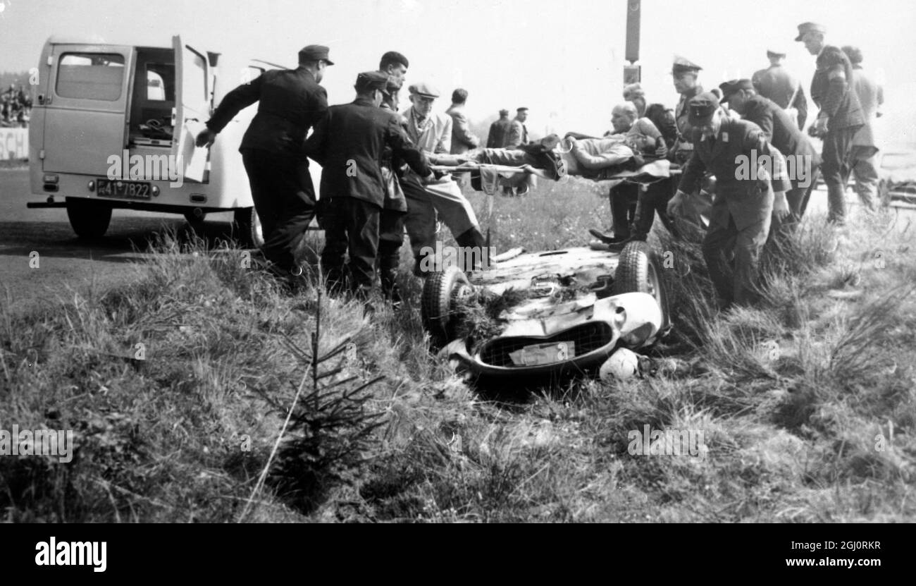 Italian racing driver , Luigi Musso , is carried from his overturned Ferrari by Red Cross men to the waiting ambulance after he overshot a curve and overturned in the third lap , escaping without serious injury , during the International 1000 kilometre car race at the famous track here . 56 cars were entered in the race from 12 countries and Mike Hawthorn driving a Jaguar was amongst the British contingent , Nuremberg , Germany . 27 May 1956 Stock Photo