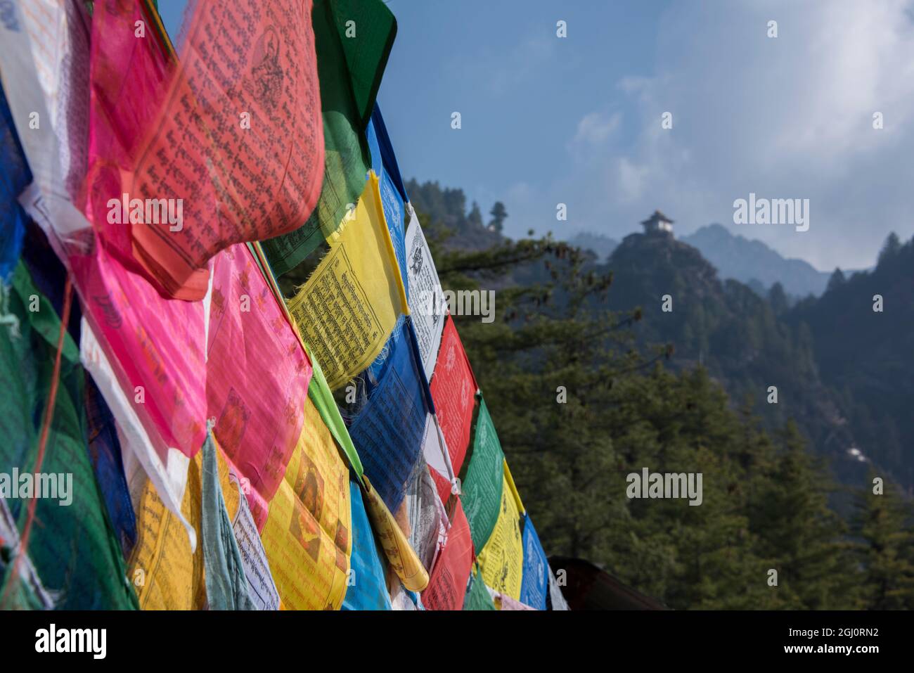 Bhutan, Paro. Colorful prayer flages in front of small outbuilding of the Tiger's Nest, sacred Himalayan Buddhist temple complex. Stock Photo