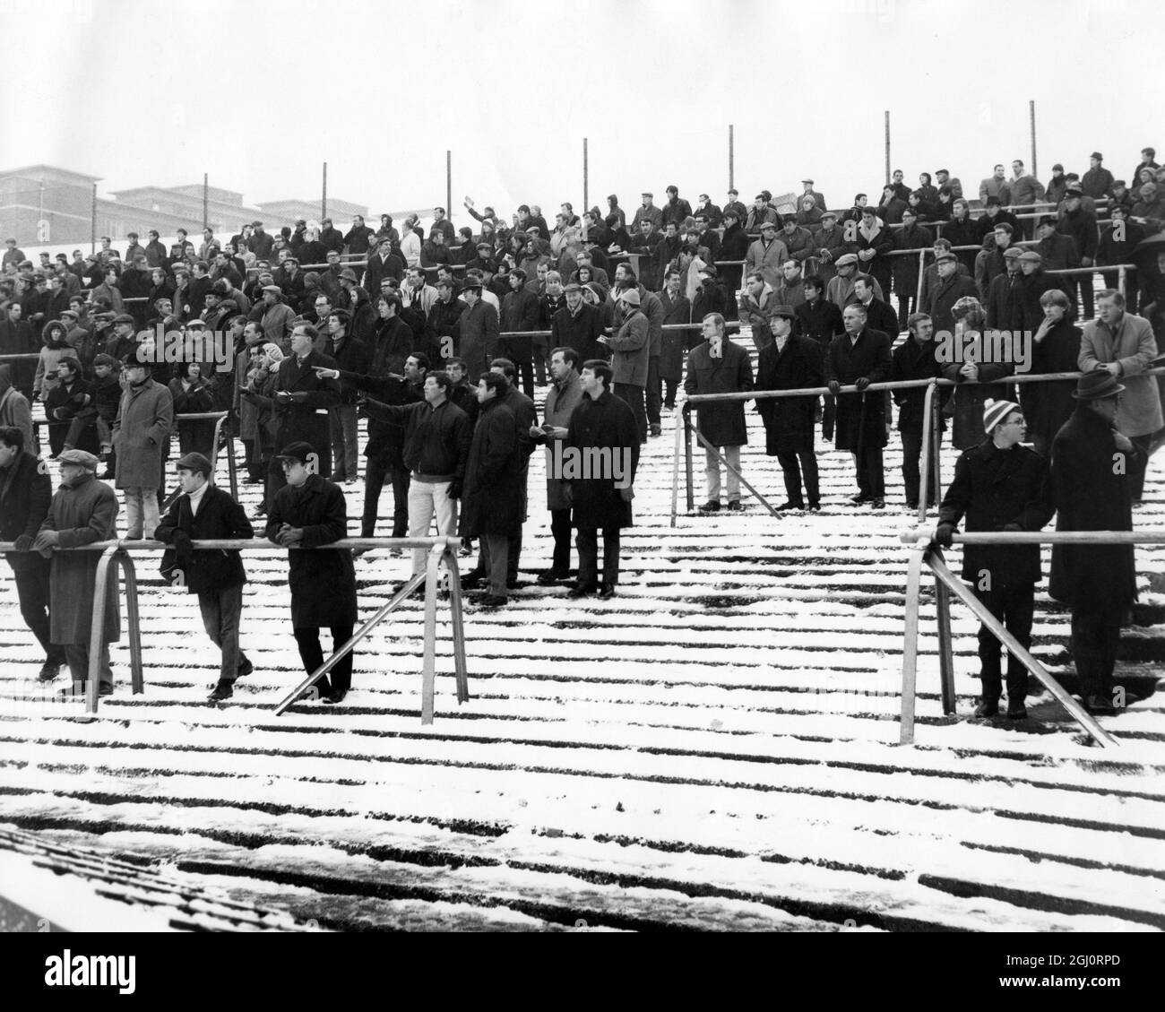 BAD WEATHER KEEPS CROWDS AT HOME . FOOTBALL AT HIGHBURY . ARSENAL V SHEFFIELD WEDNESDAY. A section of the terrace showing a few ardent supporters amongst the snow . 9 December 1967 Stock Photo
