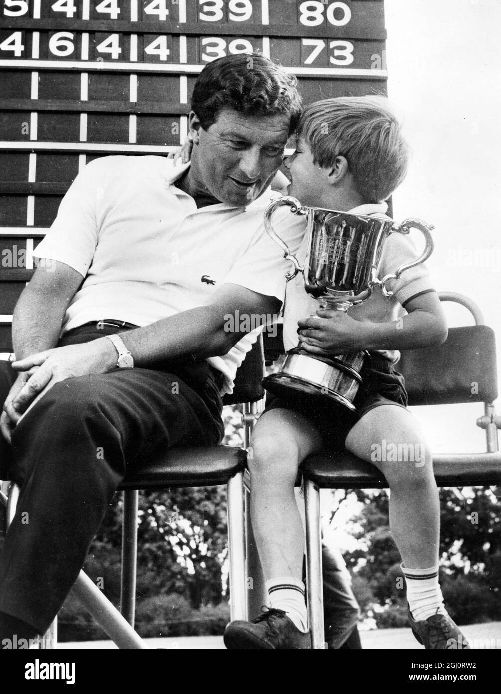 6 year old Andrew Thomson had just one big worry , would Dad bring him home another big silver cup ? And Daddy , Champion golfer Peter Thomson , didn't disappoint him . In the picture , young Andrew gives his Dad a big hug , and takes command of the Australian Open Championship Cup , which his father had won yet again . 3 November 1967 Stock Photo