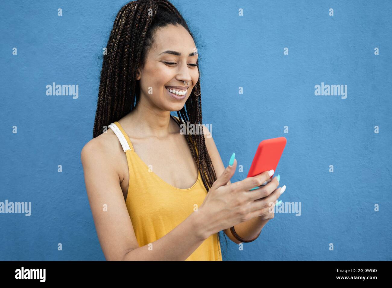 Bohemian mixed race girl using mobile phone outdoor with city in background - Focus on face Stock Photo