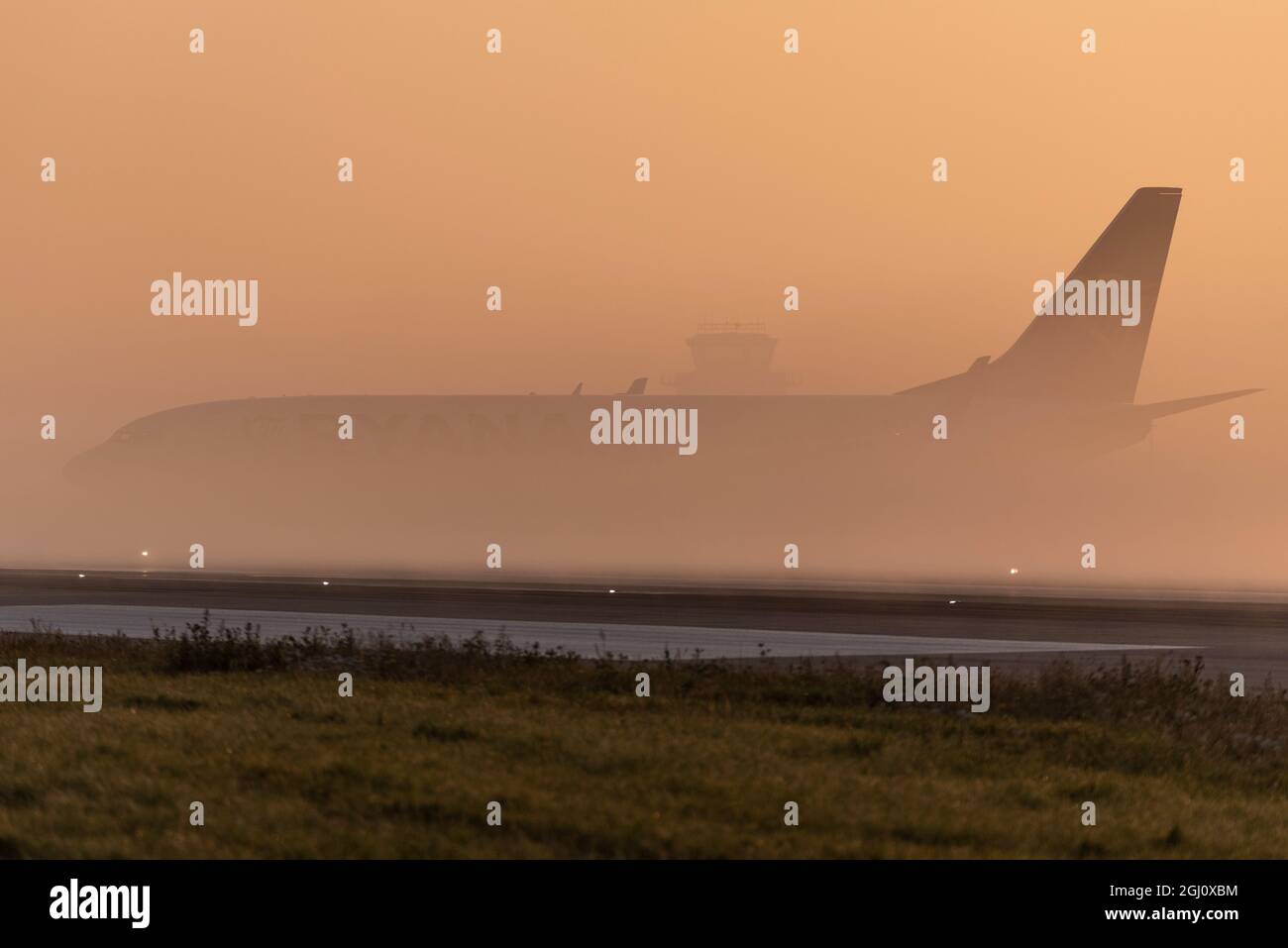 Ryanair Boeing 737 taxiing, barely visible at London Southend Airport, Essex, UK, early in the morning with low lying mist at sunrise. Bad visibility Stock Photo