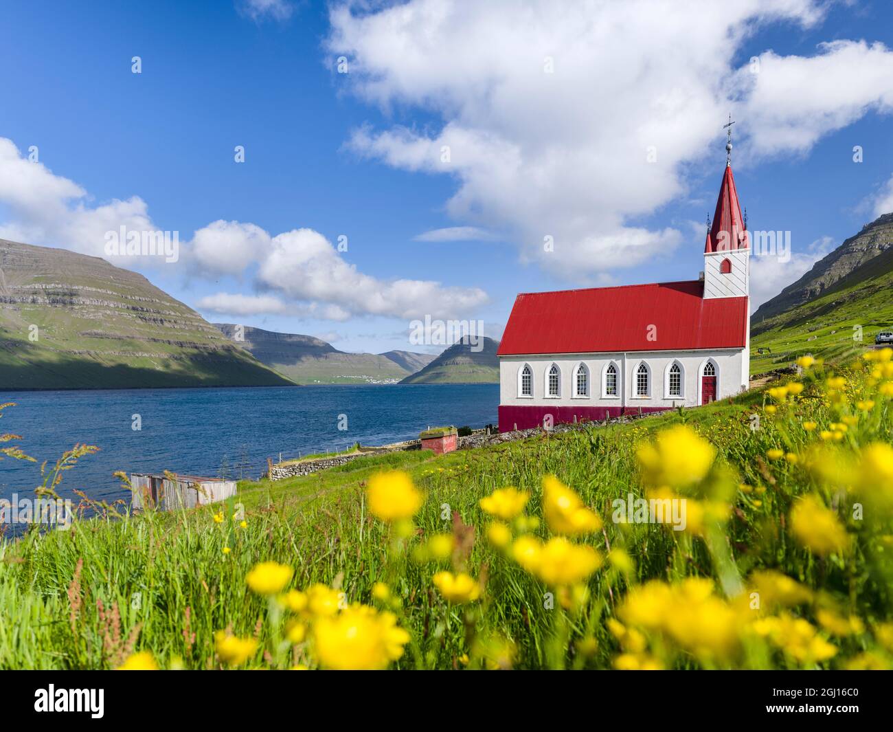 The church in village Husar on Kalsoy, in the background the island of  Bordoy and  Klaksvik. Nordoyggjar (Northern Isles) in the Faroe Islands, an ar Stock Photo