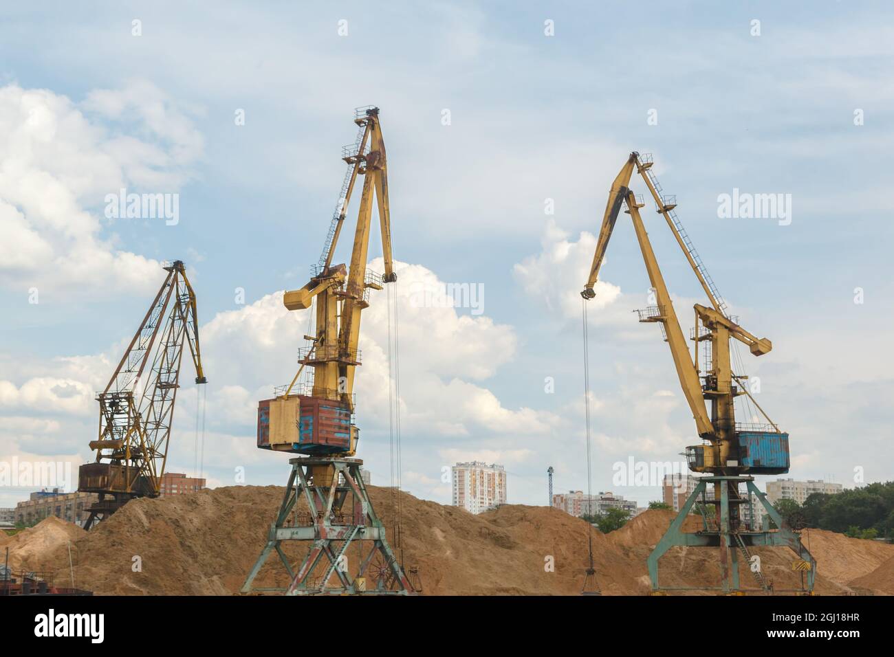 Three port crane loading sand. Urban landscape Stock Photo - Alamy