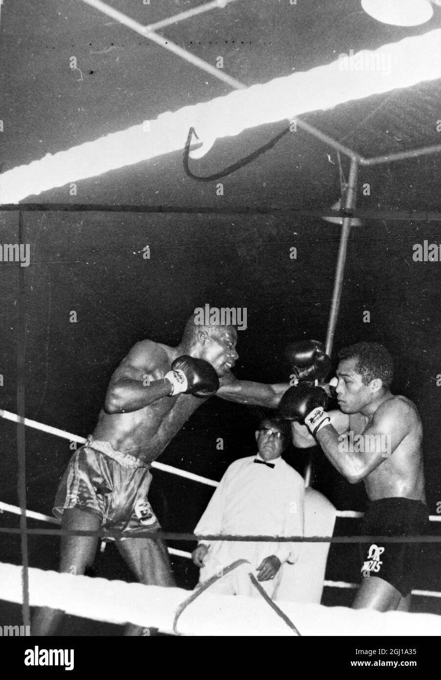 JACK HART BOXING REFEREE WITH BOXERS FLOYD ROBERTSON V SUGAR RAMOS IN ACTION IN ACCRA, GHANA ; 13 MAY 1964 Stock Photo