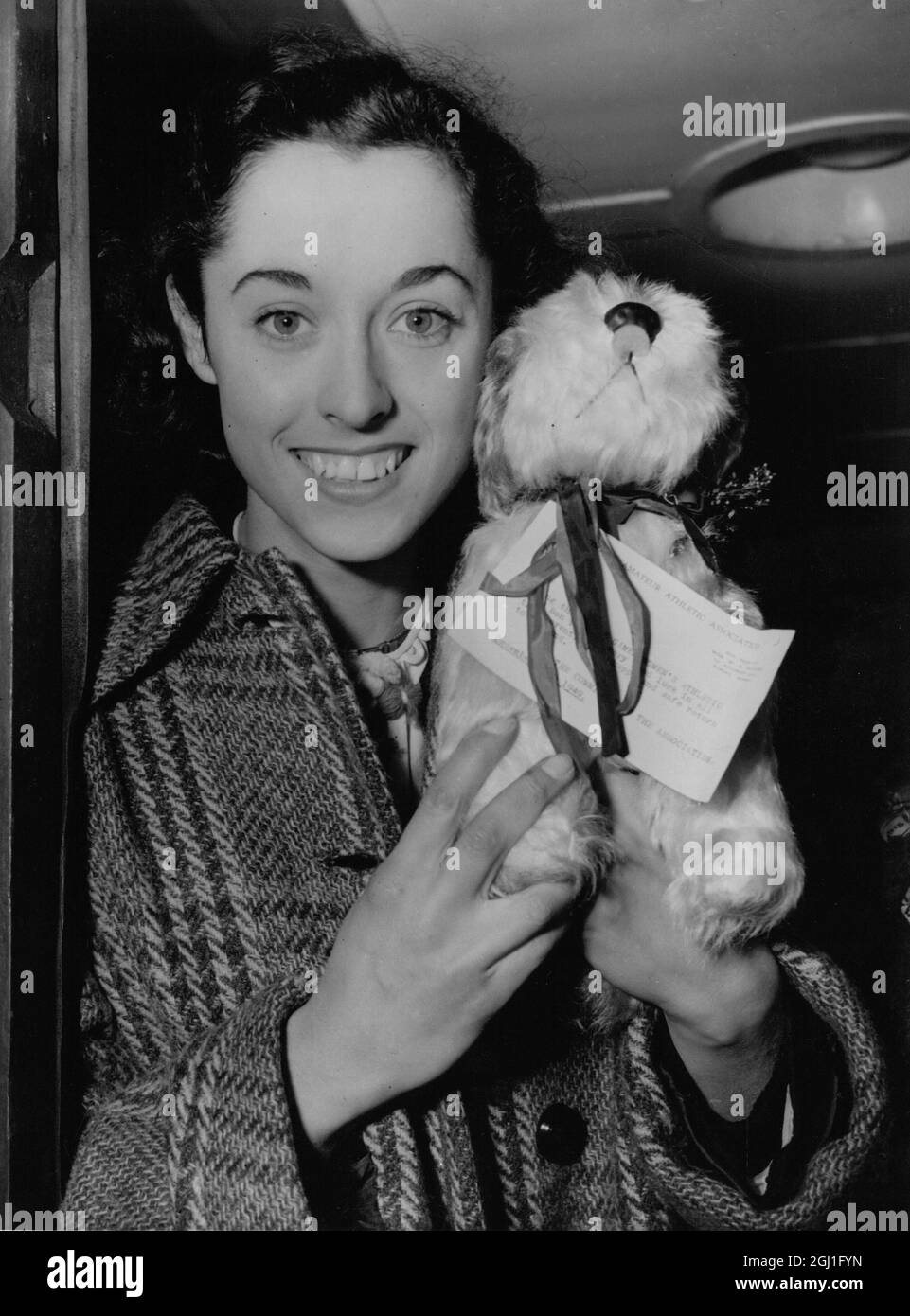 Sylvia Cheeseman , national 100 and 200 metres champion , with '' Owd Bob '' the dog mascot presented to the team by the Amateur Athletic Association , as she left Waterloo Station . 16th December 1949 Stock Photo