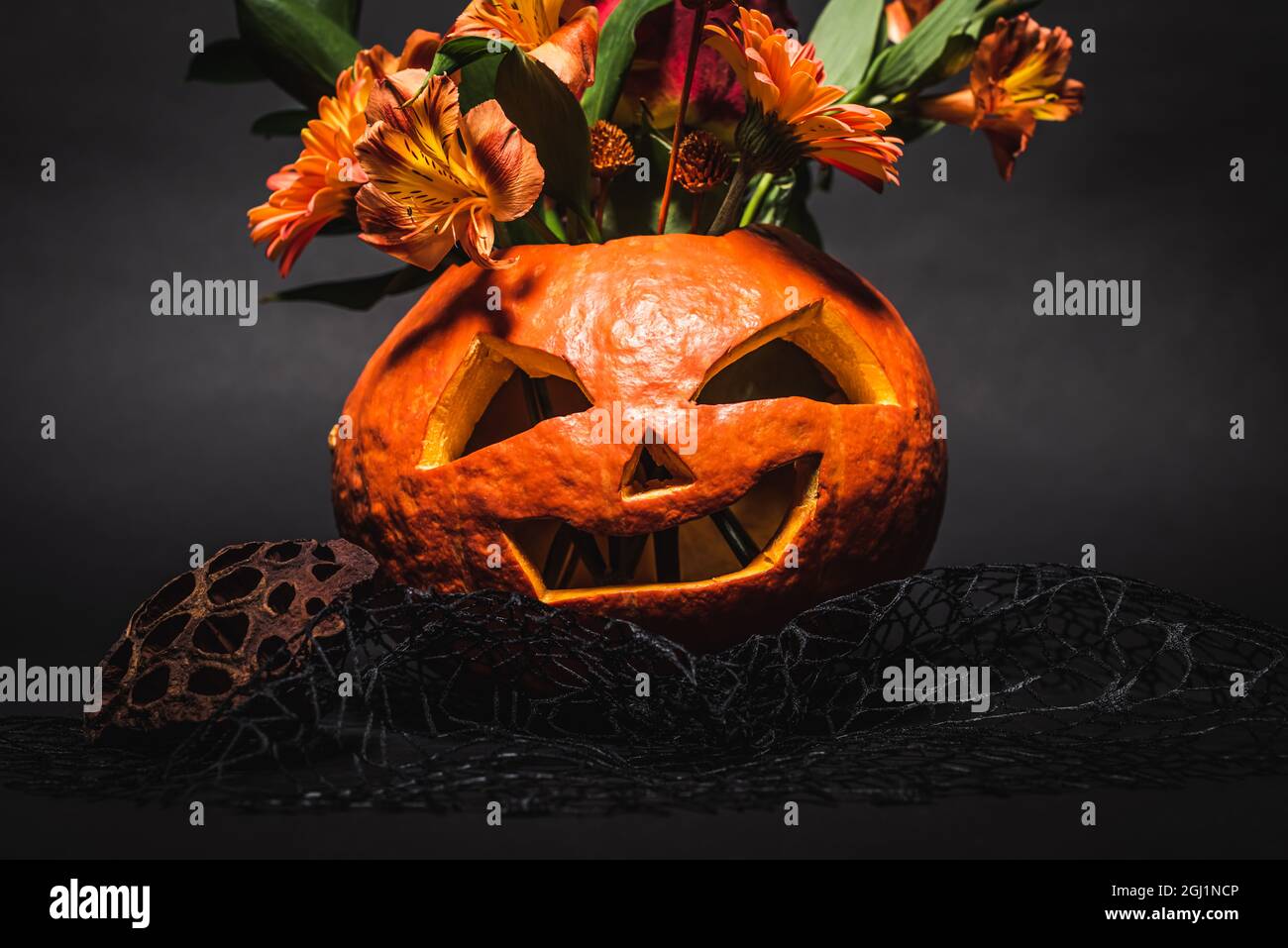 flowers in spooky and carved orange pumpkin on black background Stock ...
