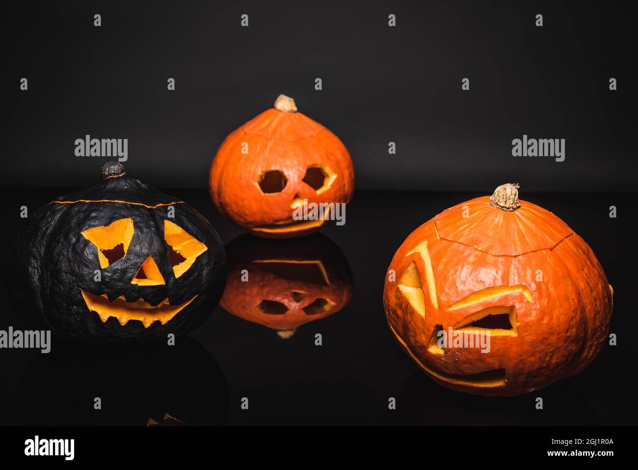 carved orange and black pumpkins on dark background Stock Photo - Alamy