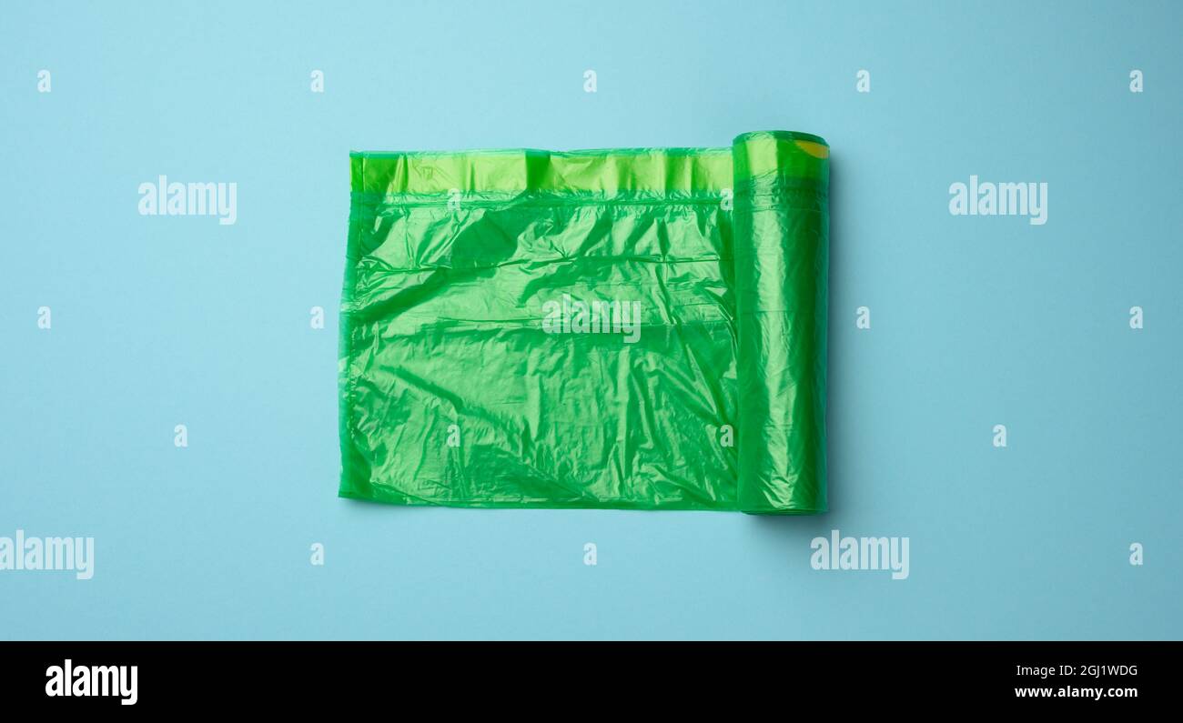 roll of green transparent plastic bags for trash can on blue background