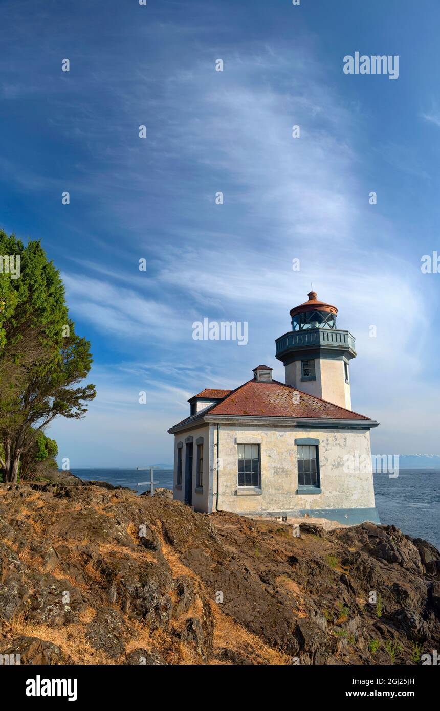 USA, Washington, San Juan Island, Lime Kiln Point State Park, Lime Kiln Point Lighthouse and rocky shoreline beneath a cirrus filled sky. Stock Photo