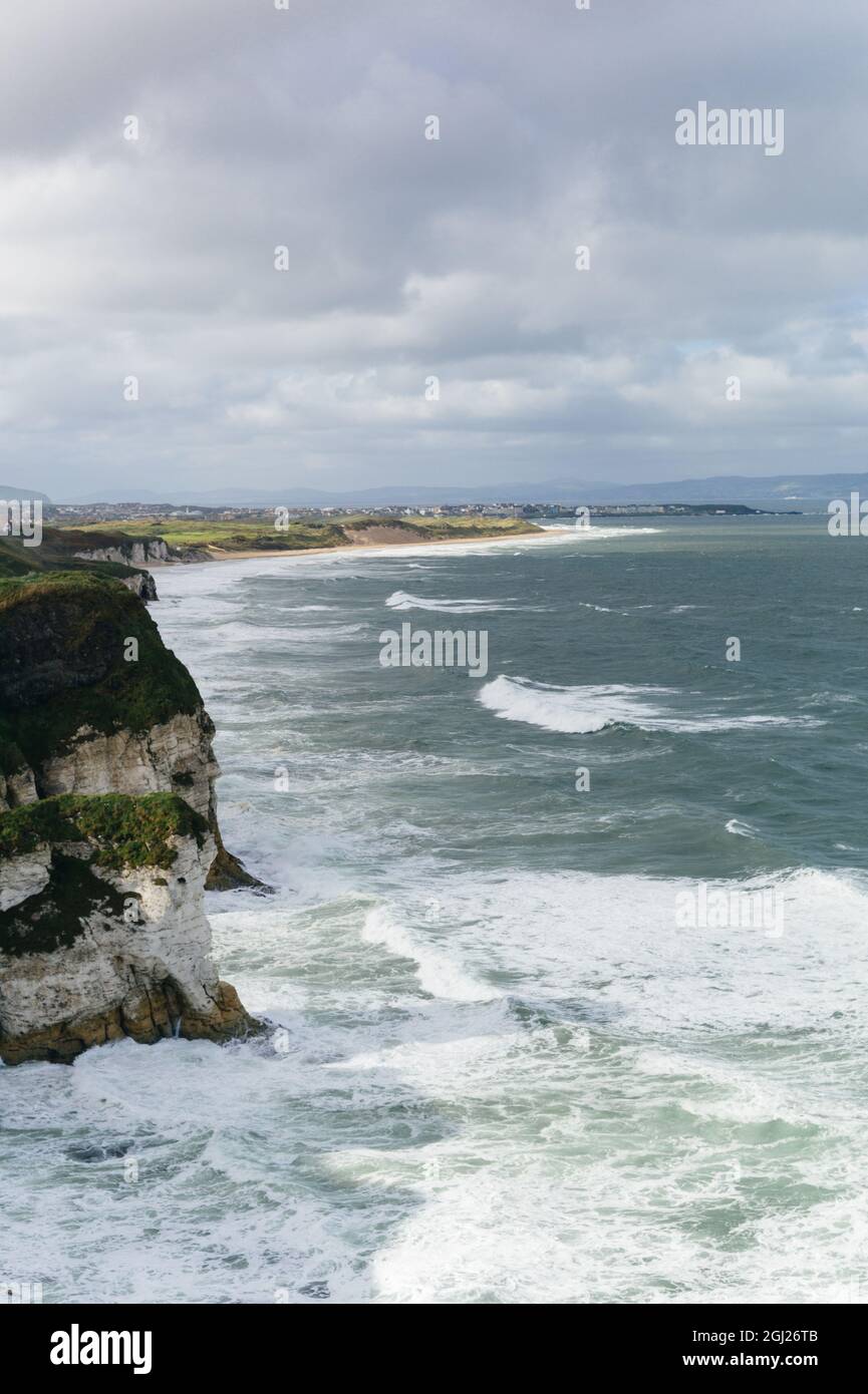 View along the Causeway Coast towards Portrush with stormy sky and waves breaking against the cliffs and beaches of Northern Ireland. Stock Photo
