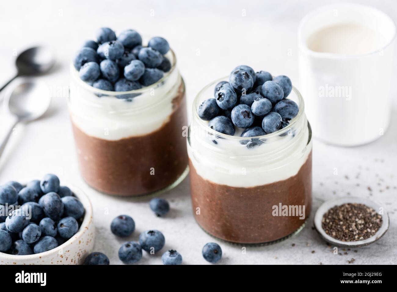 Chocolate chia pudding with yogurt layer and blueberries in a jar, closeup view. Healthy dessert or sweet snack Stock Photo