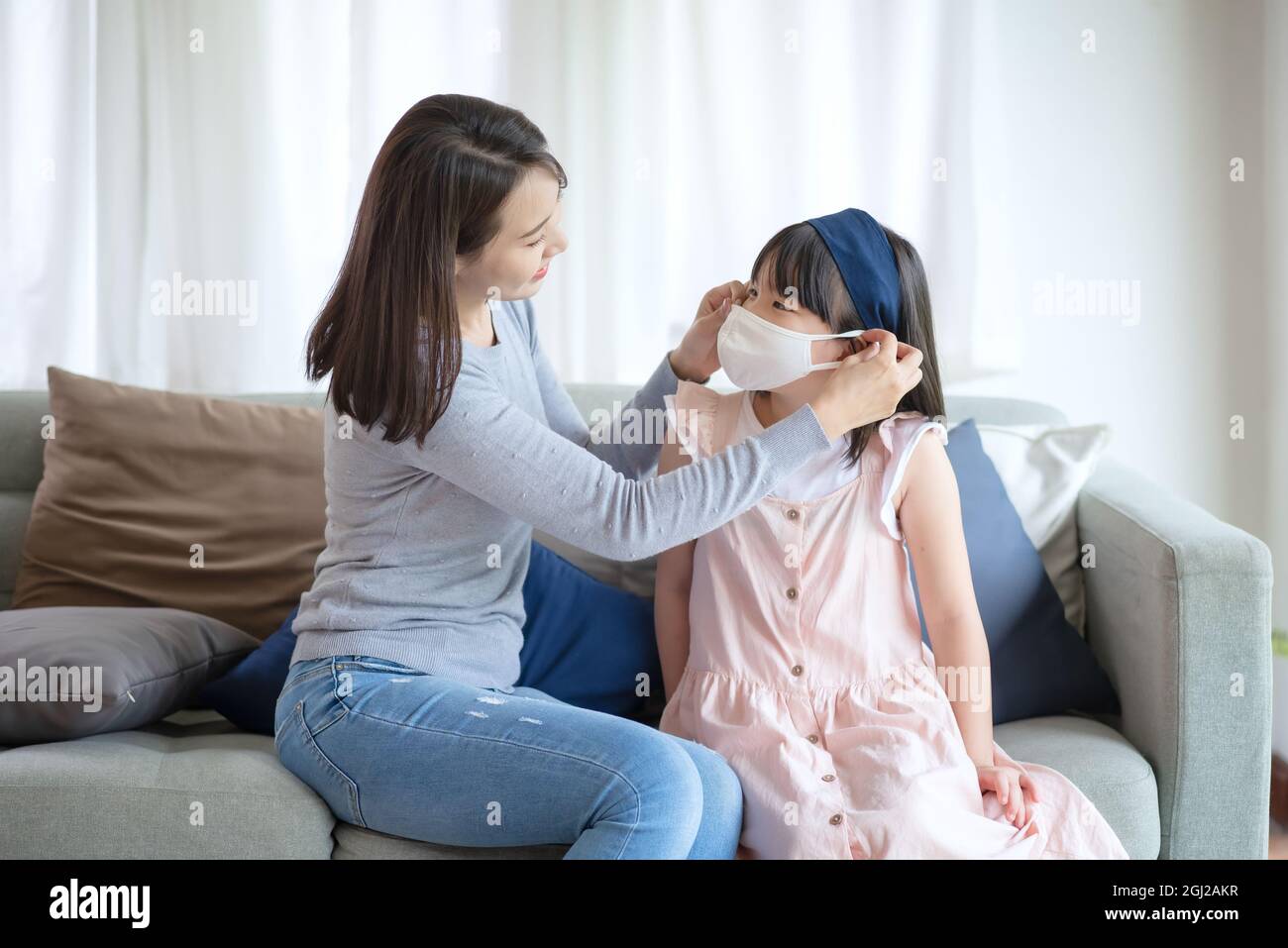 Asian mother teaching her daughter to wear hygienic face mask for prevent coronavirus or Covid-19 Stock Photo
