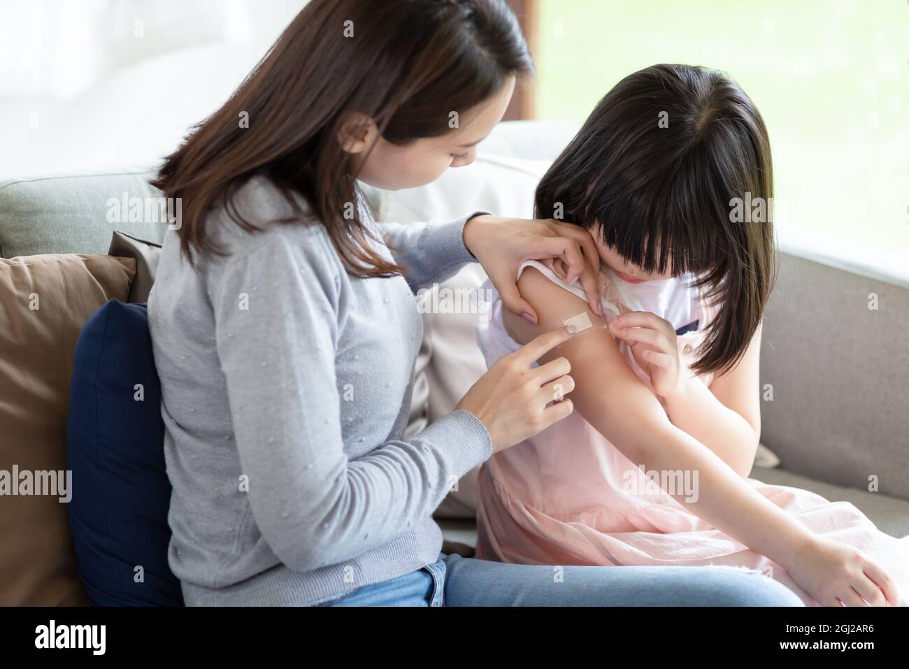 Asian mother putting court plaster adhesive bandage onto her daughter at home Stock Photo