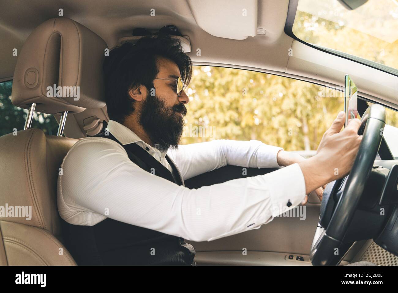 Stylish and successful Indian in a stylish suit driving a luxury car