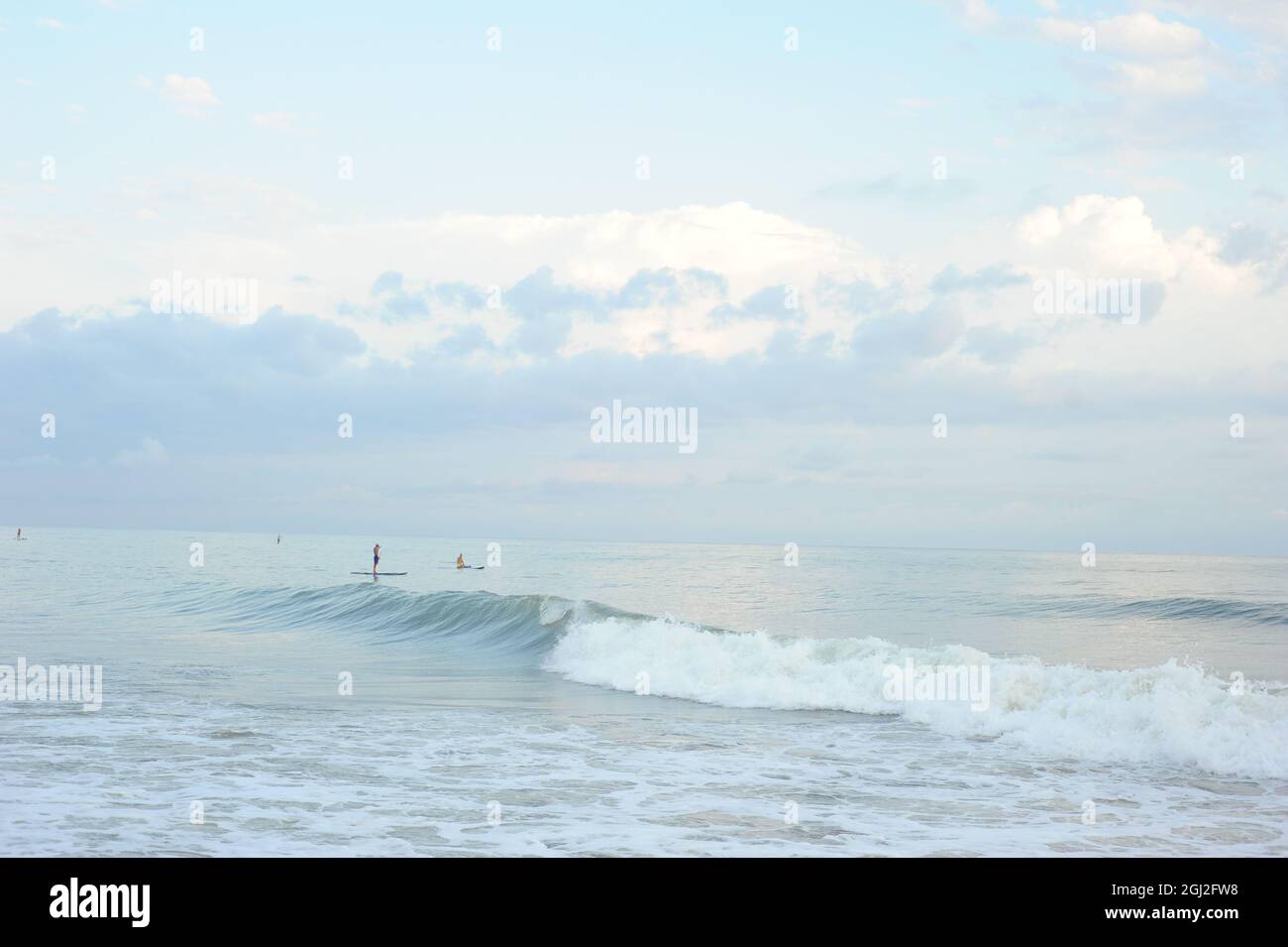 Black Sea in Abkhazia. Small figures of surfers. Blue pastel sunset. Rest on the sea. Stock Photo