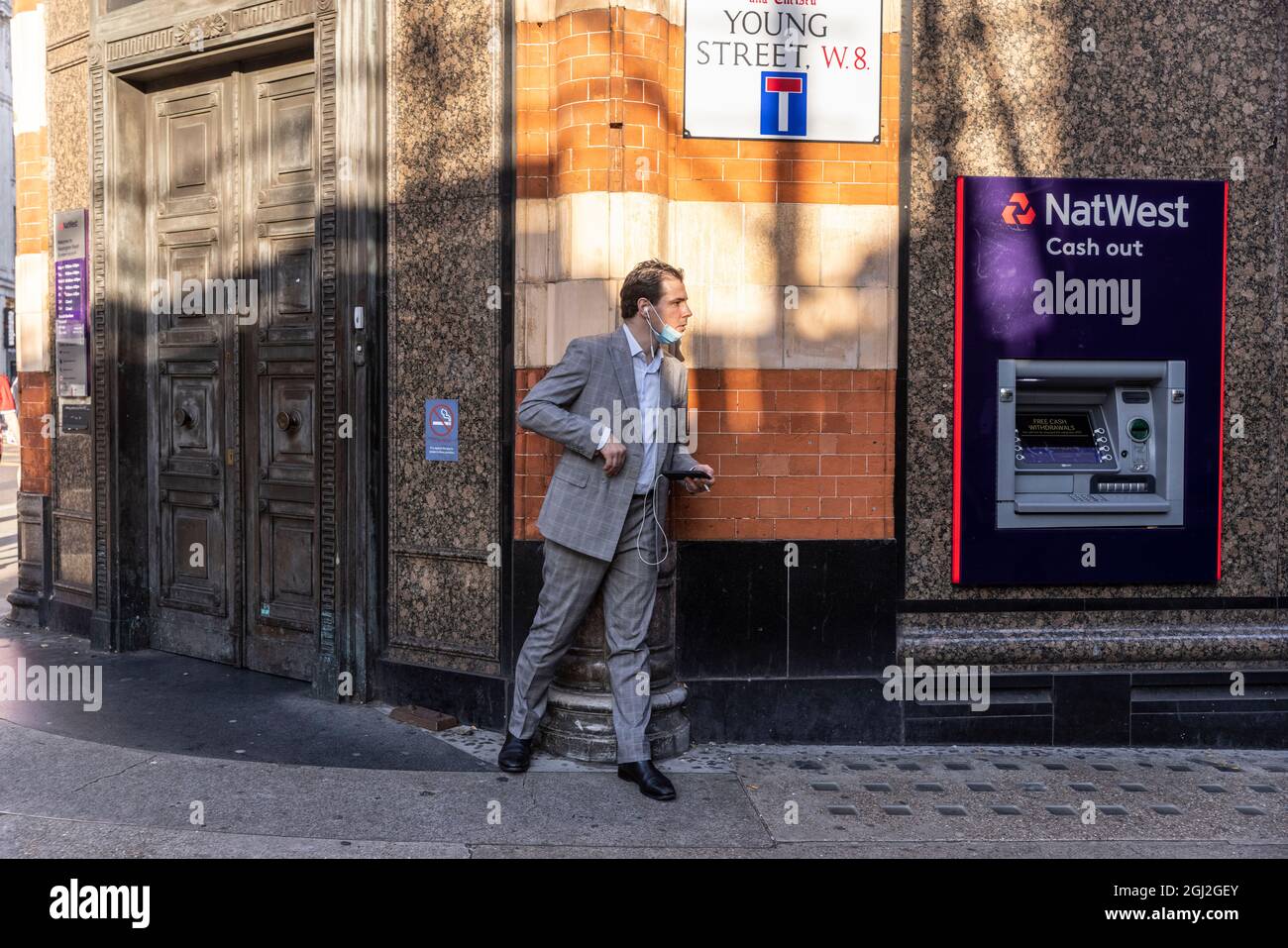 Businessman lurking behind the corner of a wall on Young Street, Kensington, Central London, United Kingdom Stock Photo