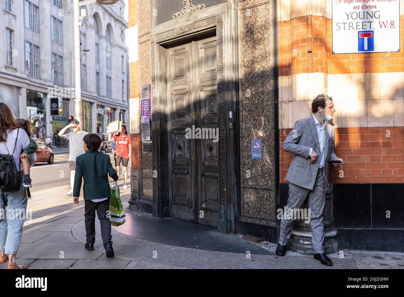 Businessman lurking behind the corner of a wall on Young Street, Kensington, Central London, United Kingdom Stock Photo