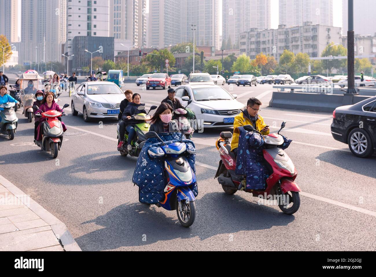 People on electric bicycle with colourful windshield on crossroad, Hefei, China. Stock Photo