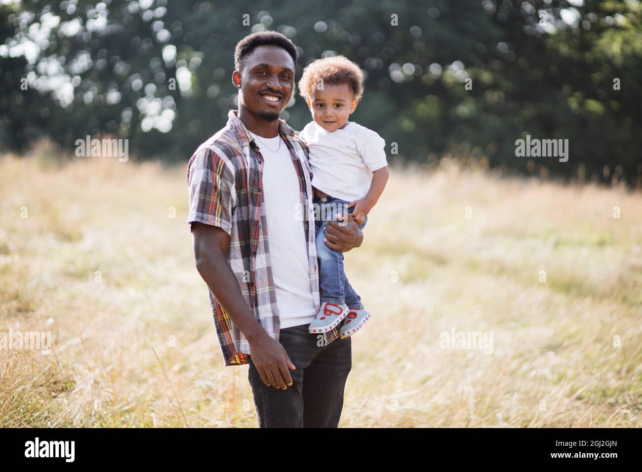 Front view of happy african american father holding his little son on ...