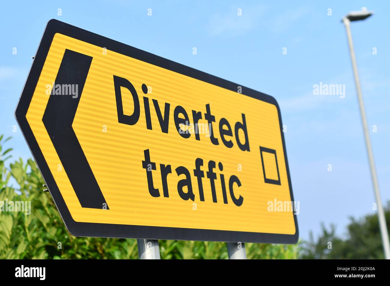 An angled view of a road traffic directional sign in yellow stating Directed Traffic with a blue sky in the background Stock Photo