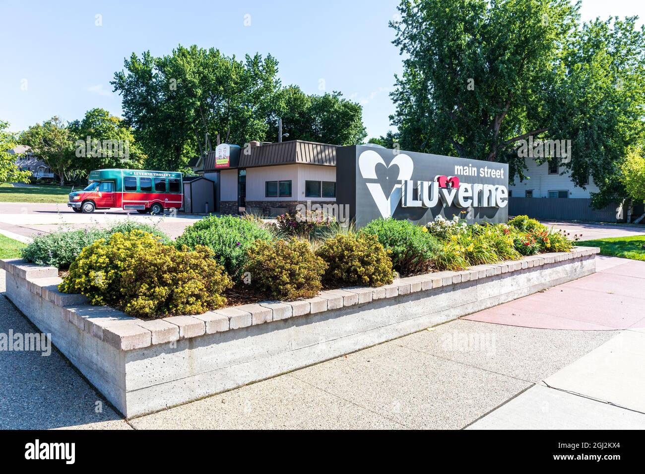 LUVERNE, MN, USA-21 AUGUST 2021: Monument sign for Luverne's main street set in a planter, with the Laverne Trolley (bus) in background. Stock Photo