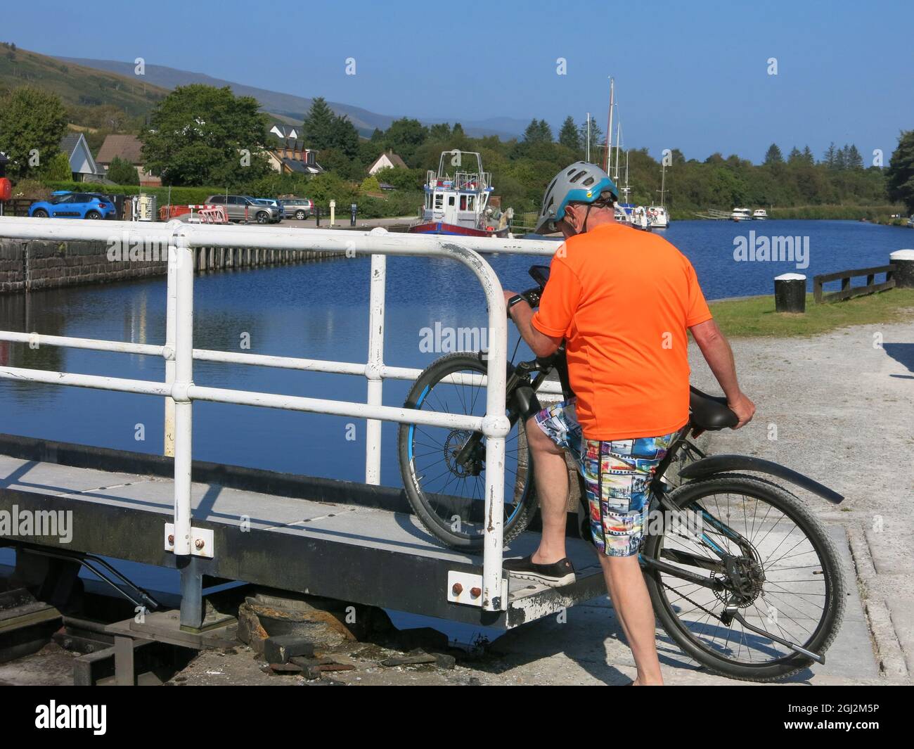 A cycling holiday in the Highlands and Islands: a cyclist takes his bike across the lock gates over the Caledonian Canal at Neptune's Staircase. Stock Photo