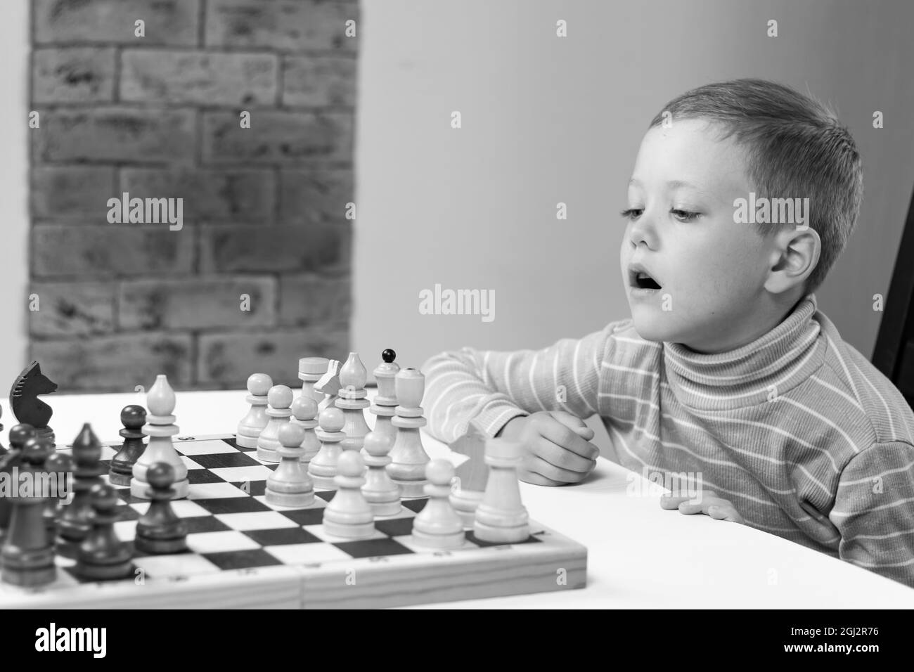 Cute seven year old child boy playing chess at home on a white wooden table. Selective focus. Close-up. Portrait Stock Photo