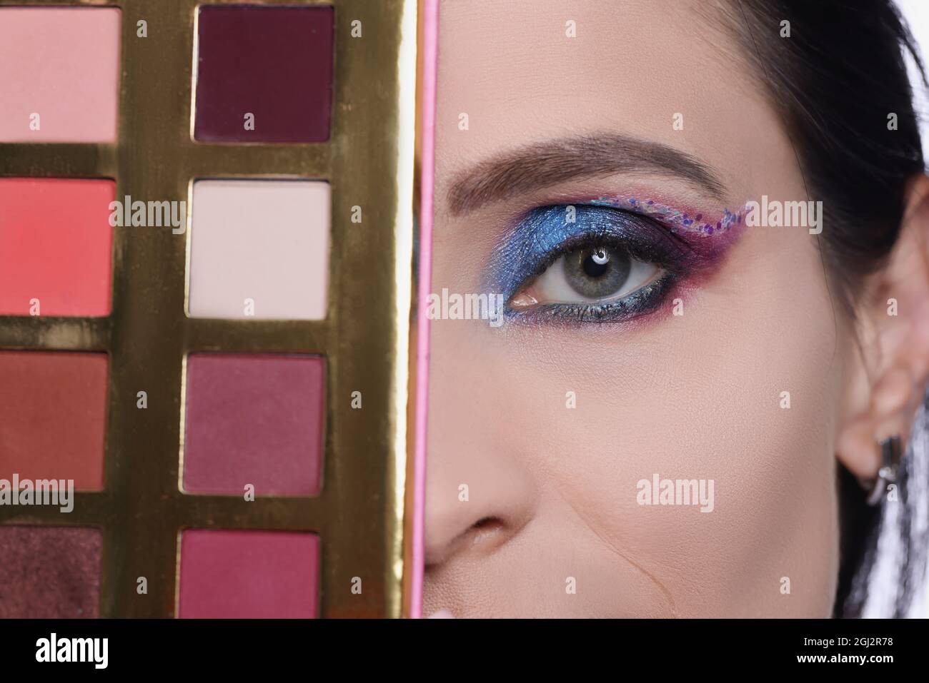 Woman with evening make-up holds eye shadow palette closeup Stock Photo
