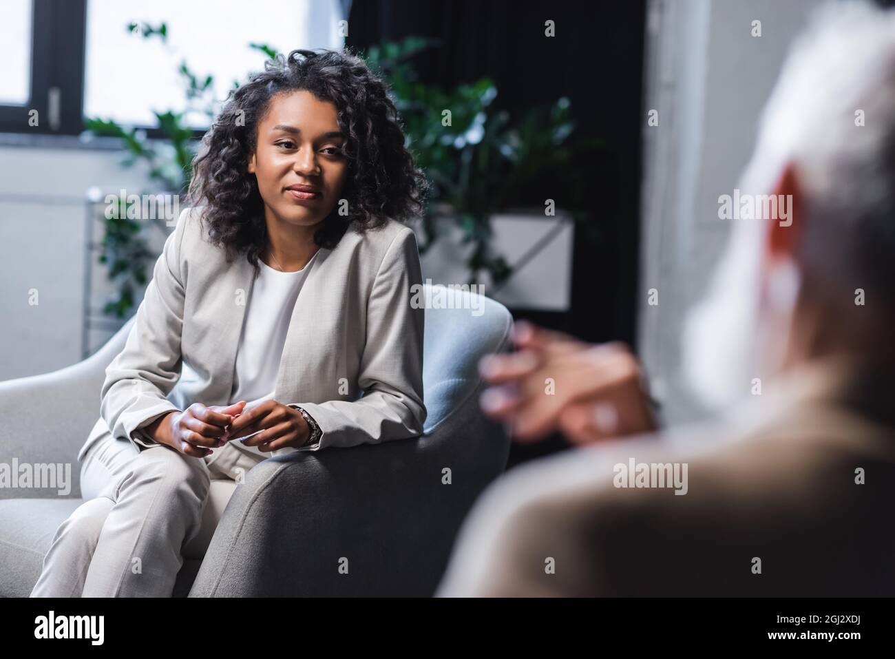 pretty african american journalist looking at blurred businessman