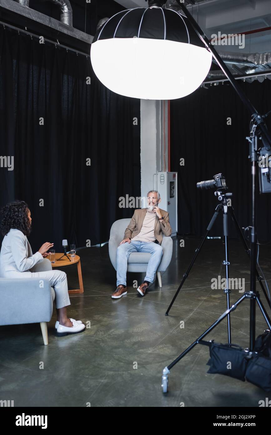 african american journalist talking with businessman sitting in grey
