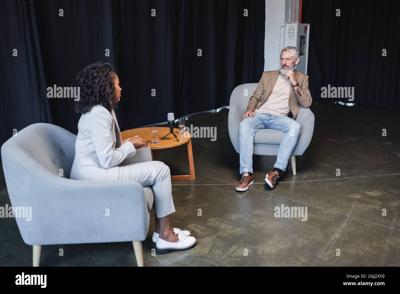 curly african american journalist in suit talking with businessman